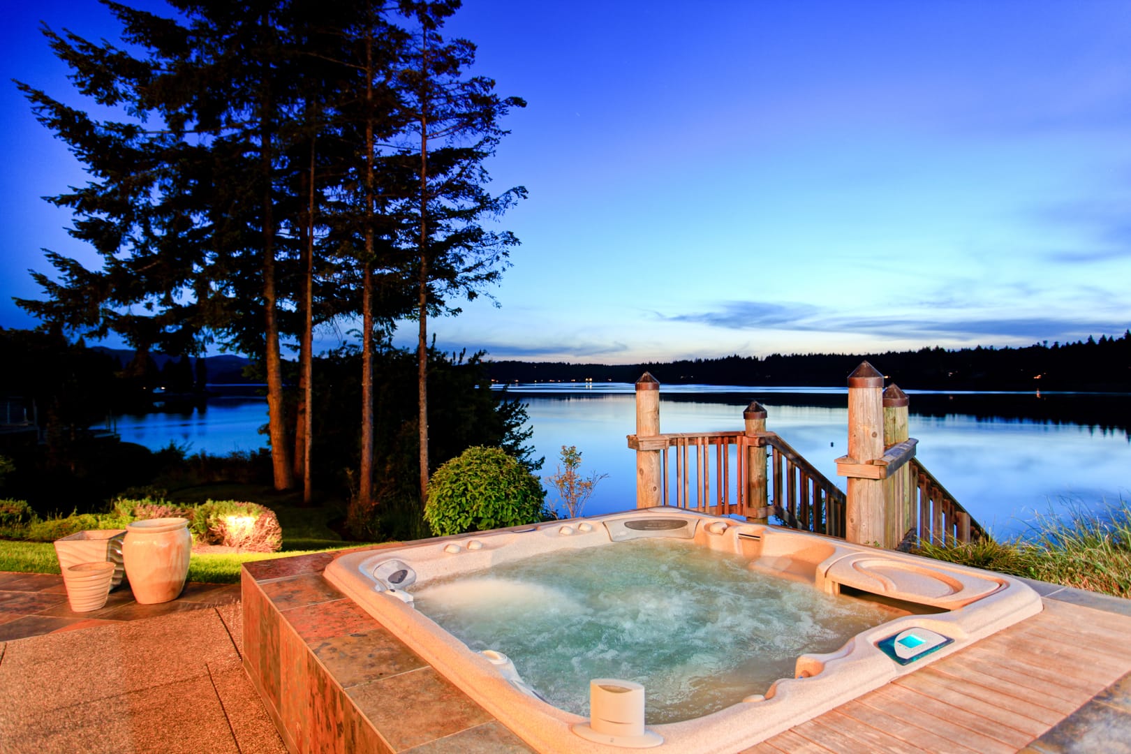 Hot tub on a deck overlooking a lake at dusk